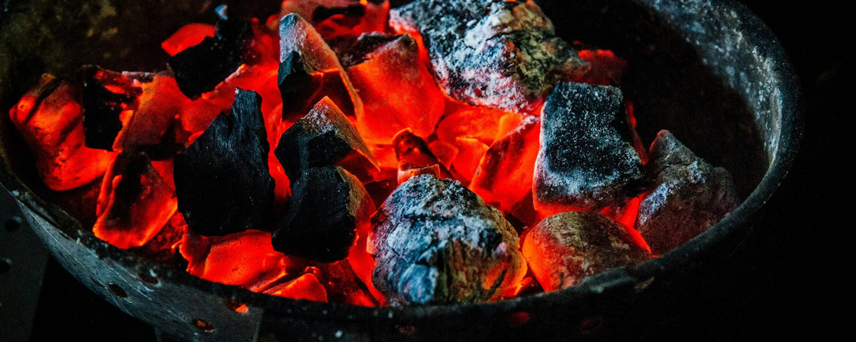 Jak rozpalić kamado: żarzące się kawałki węgla drzewnego w okrągłym koszu na węgiel